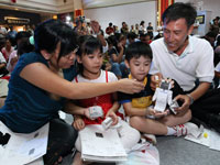 Family of four piecing an ASIMO origami together to win a photo opportunity with ASIMO.